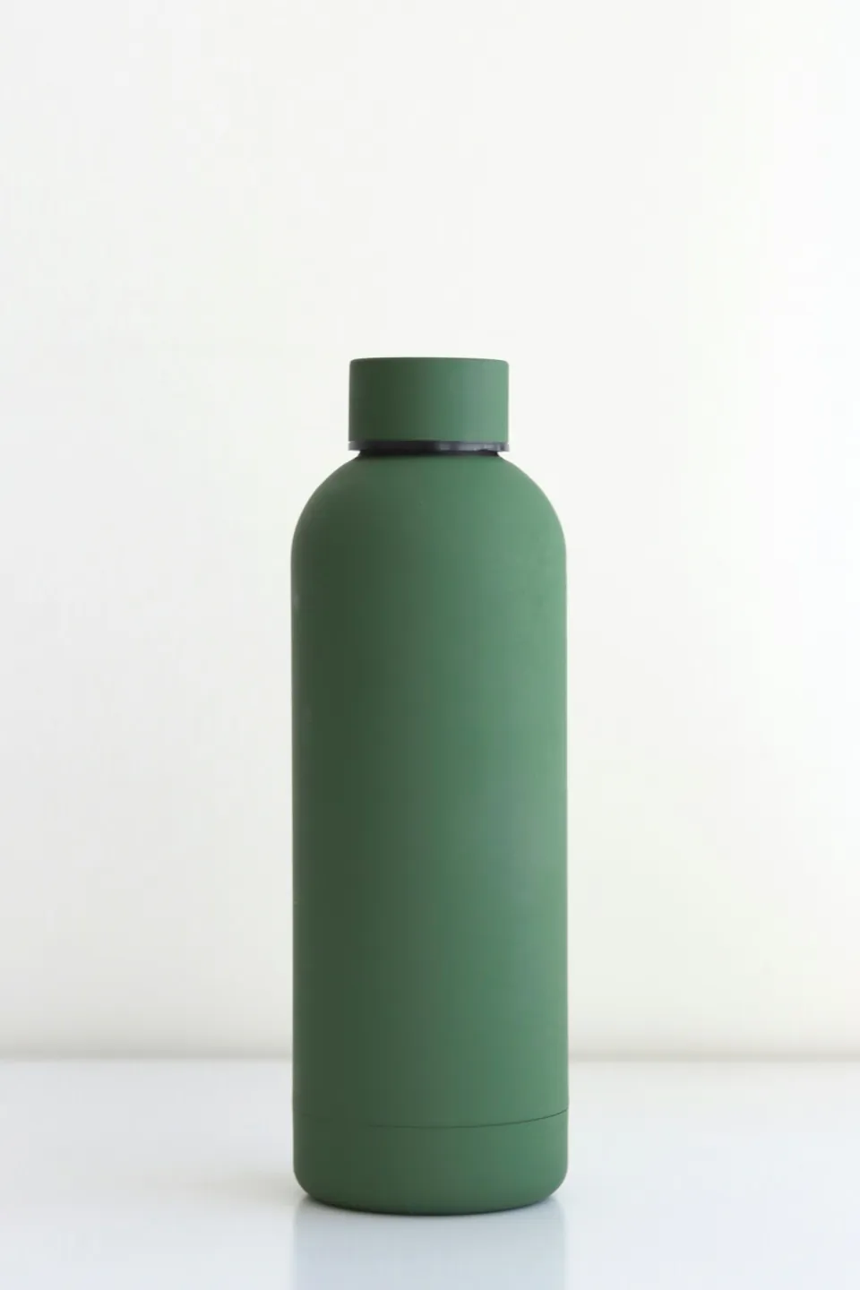 Green reusable bottle photographed against a white studio background